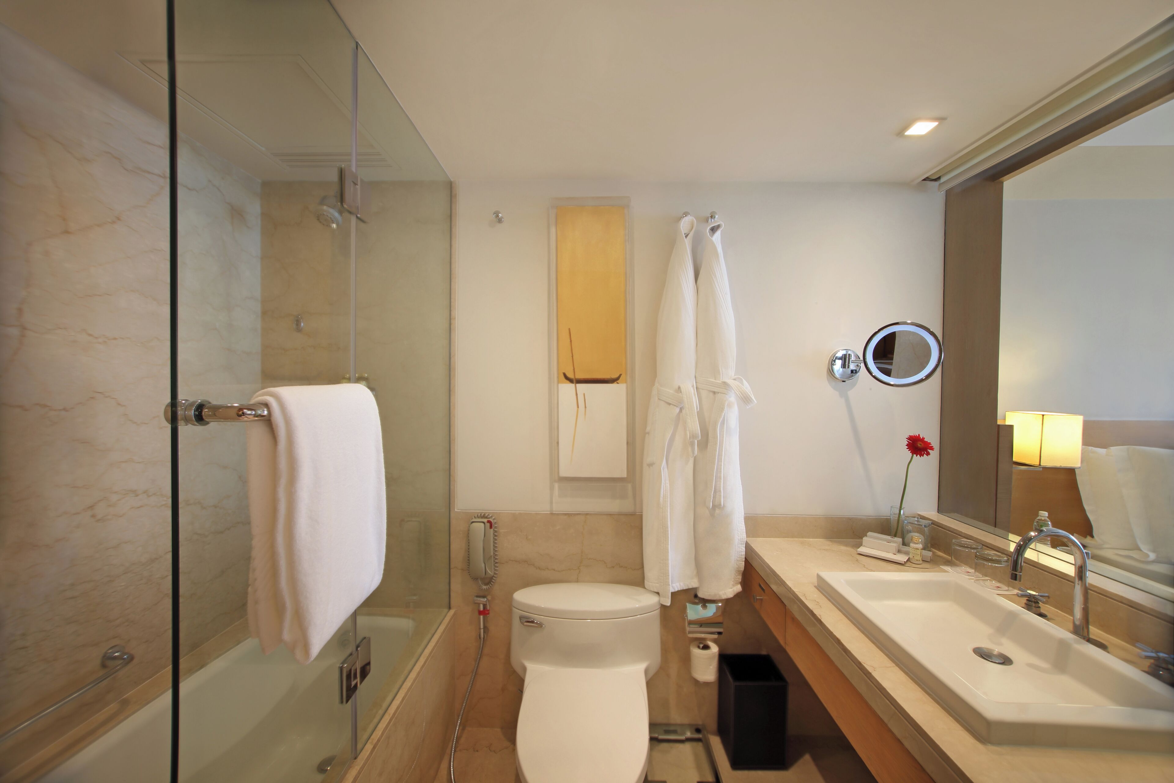 A modern bathroom with a glass-enclosed shower, a white toilet, a sink with a mirror, and a towel rack.