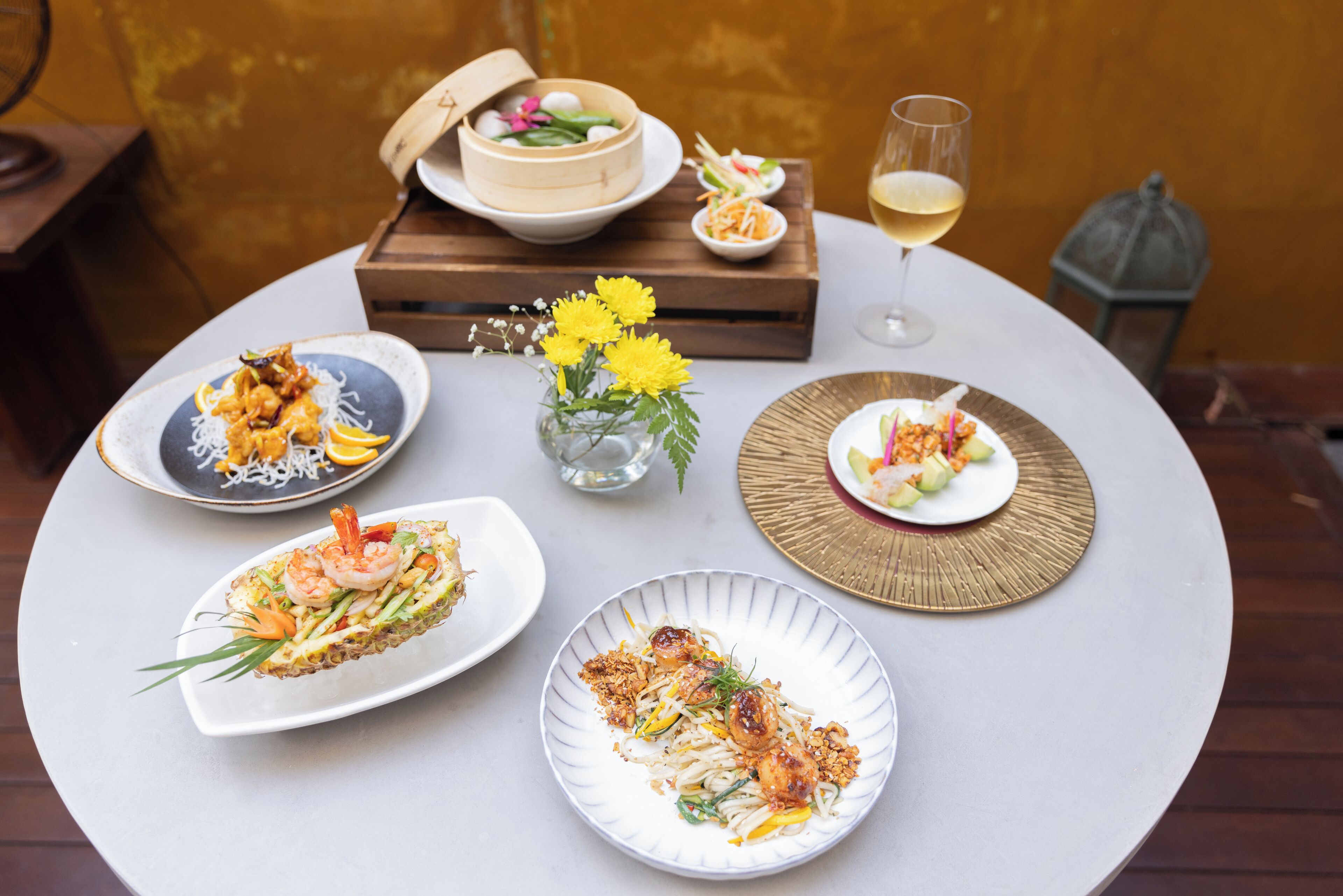 A table set with various dishes, a glass of wine, and a decorative lantern.