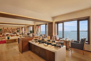 A spacious hotel lobby with a large buffet, seating areas, and a view of the sea. - Trident, Nariman Point Mumbai (Mumbai)
