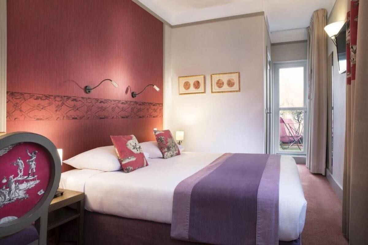 Une chambre d’hôtel avec un lit, une table de chevet, une chaise et une fenêtre avec des rideaux.