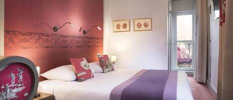 A hotel room with a bed, a nightstand, a chair, and a window with curtains.