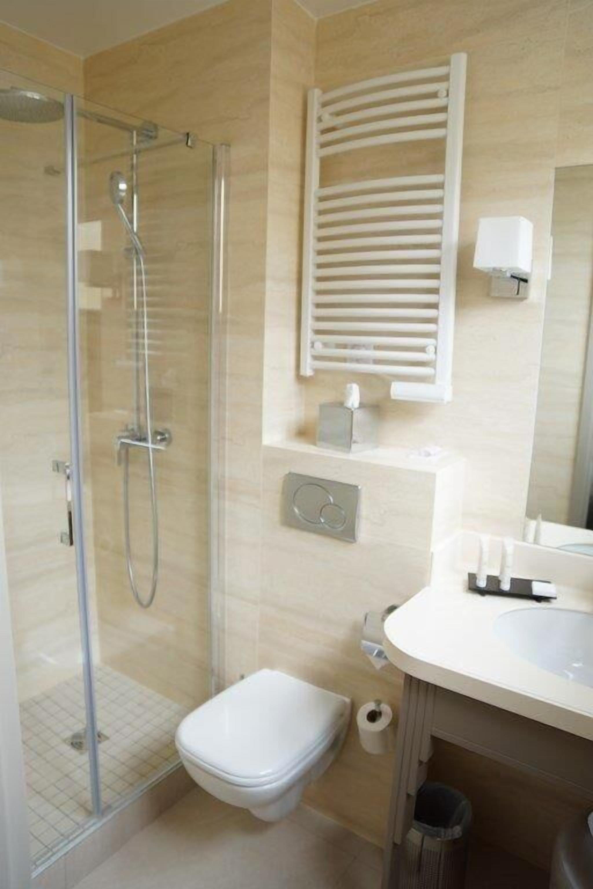 Un baño moderno con cabina de ducha de vidrio, inodoro y lavabo con espejo.