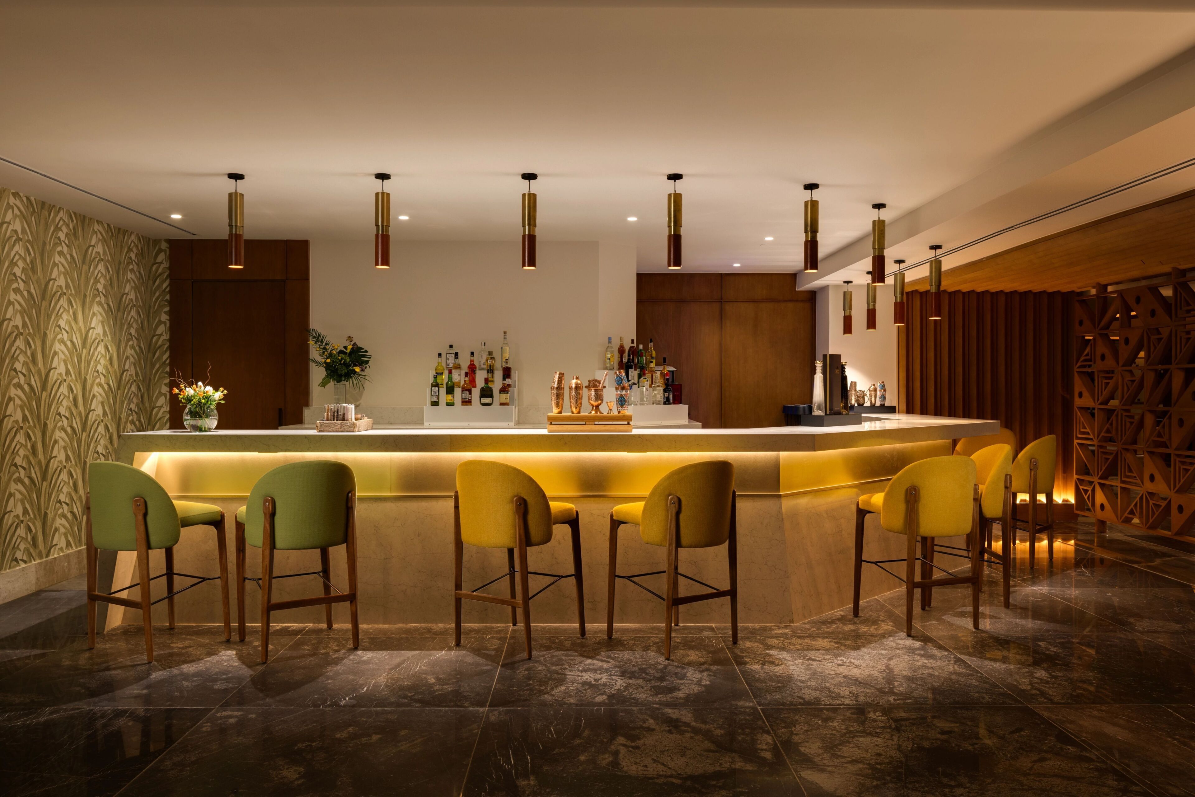 A bar area with a counter, multiple chairs, and hanging pendant lights.