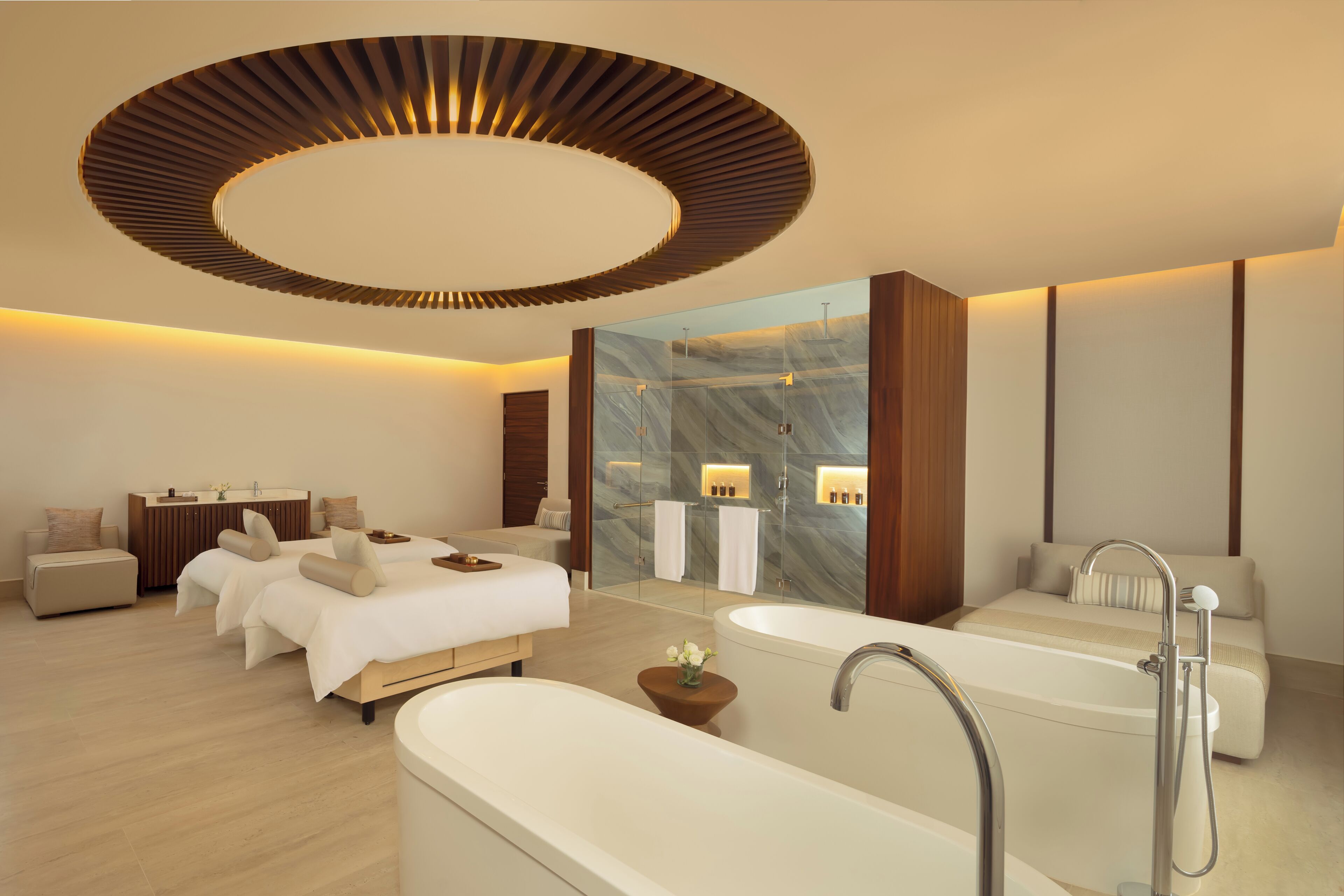 Une chambre d’hôtel moderne dotée d’un grand lit, d’un coin salon séparé, d’une baignoire et d’un grand miroir.