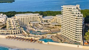 A resort with multiple buildings, a central pool, and a beach area.