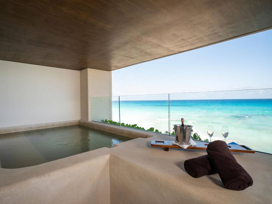 A modern bathroom with a large bathtub, a glass-enclosed shower, and a view of the ocean.