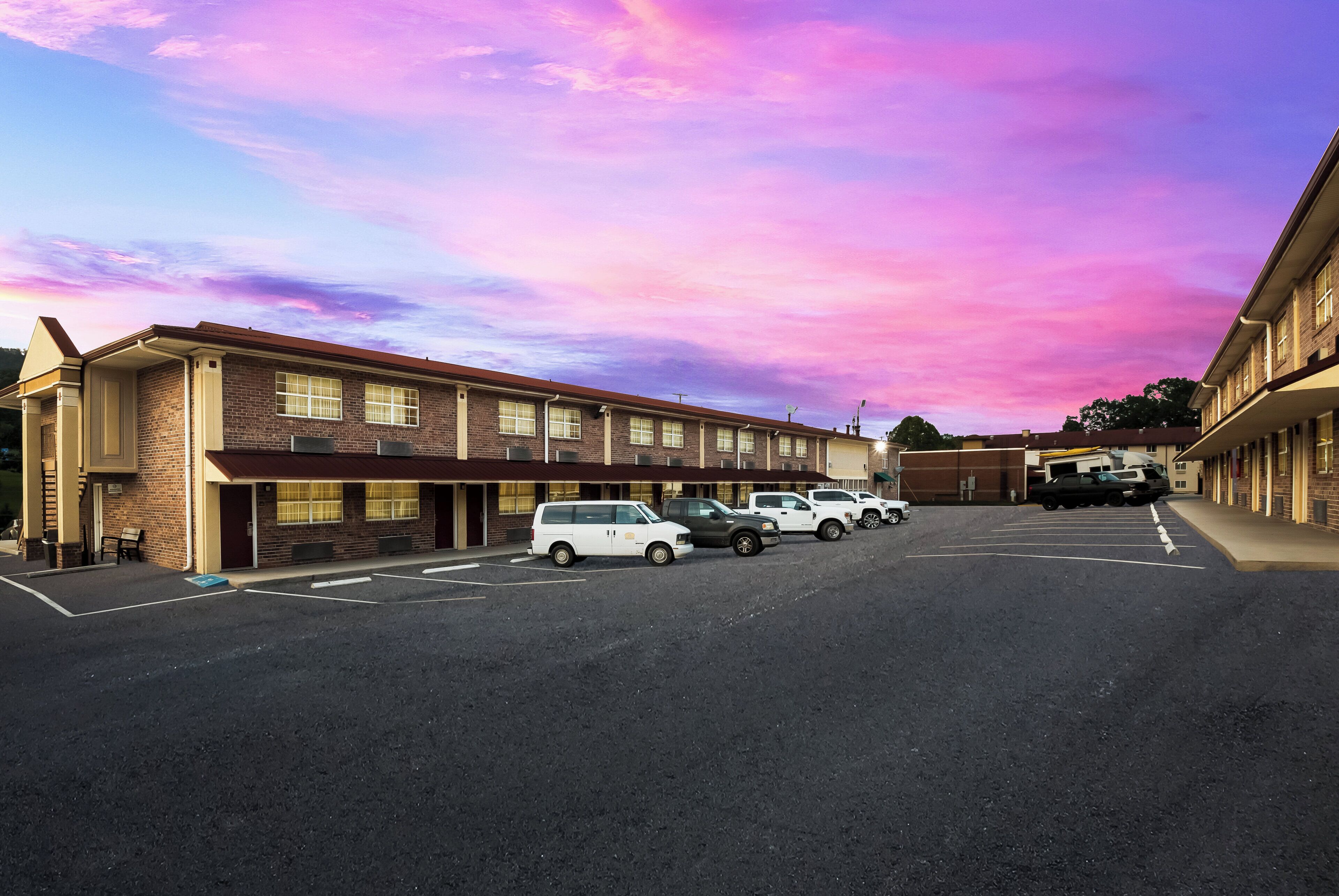 Un motel avec une rangée de places de stationnement et une rangée de chambres au rez-de-chaussée.