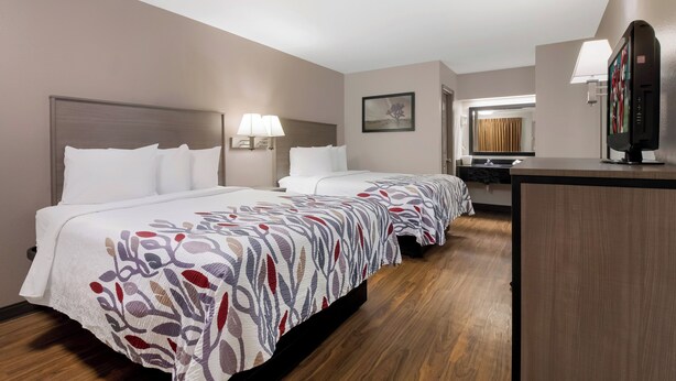 Habitación de hotel con dos camas, un escritorio, un espejo y una ventana.