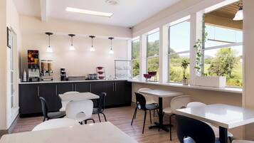 A modern kitchen with a bar area, large windows, and a view of the outdoors.