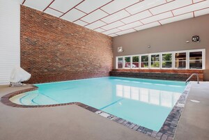 Una piscina interior con pared de ladrillo y ventanas amplias.