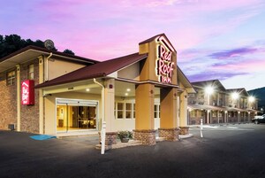 Un hotel Red Roof Inn con fachada de ladrillo, entrada cubierta y estacionamiento.