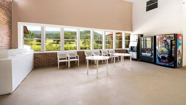 A room with a large window overlooking a green landscape, white furniture, and a vending machine. - Red Roof Inn Chattanooga - Lookout Mountain (Chattanooga)
