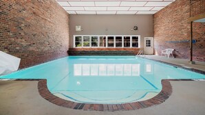 Una piscina interior con una pared de ladrillo a un lado y una ventana al otro.