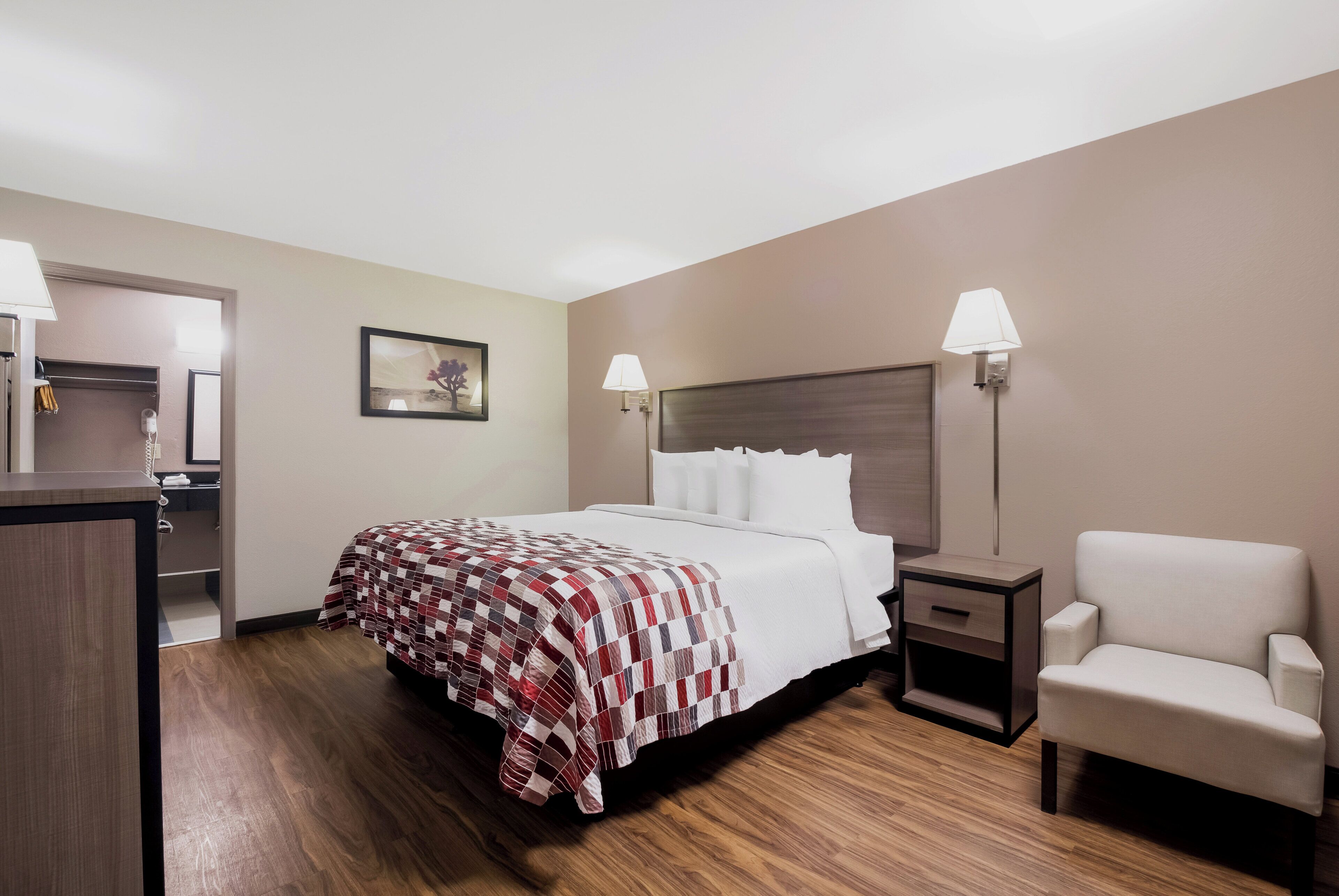 Une chambre d’hôtel avec un lit, une chaise, un bureau et une lampe.
