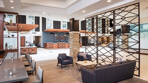 Un vestíbulo amplio con zona de bar, asientos y un separador decorativo.