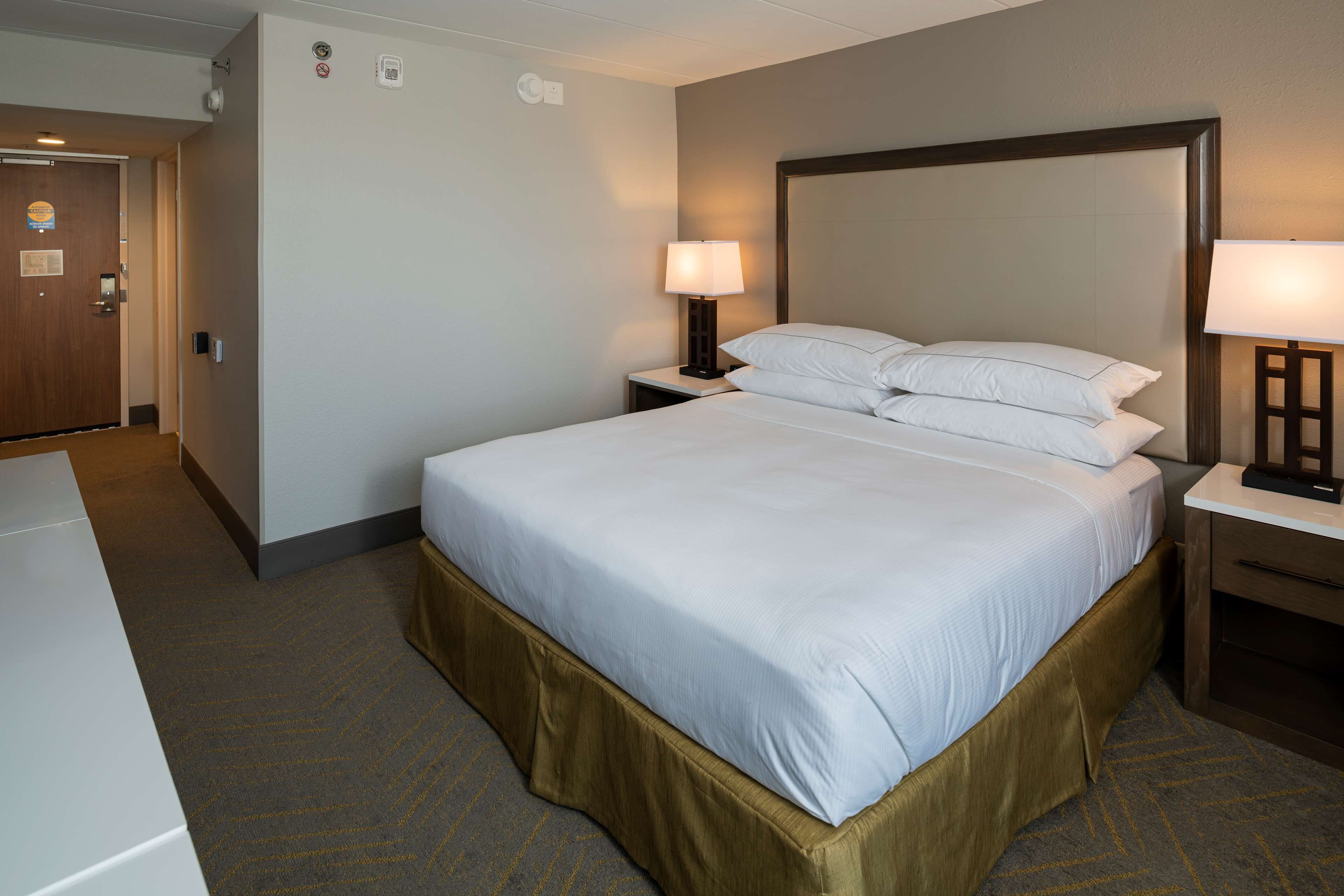 Une chambre d’hôtel avec un grand lit, deux tables de chevet et une porte.