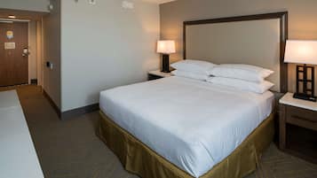 Una habitación de hotel con una cama grande, dos mesitas de noche y una puerta.