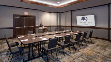 A conference room with a long table, chairs, and a projector screen displaying the DoubleTree by Hilton logo.