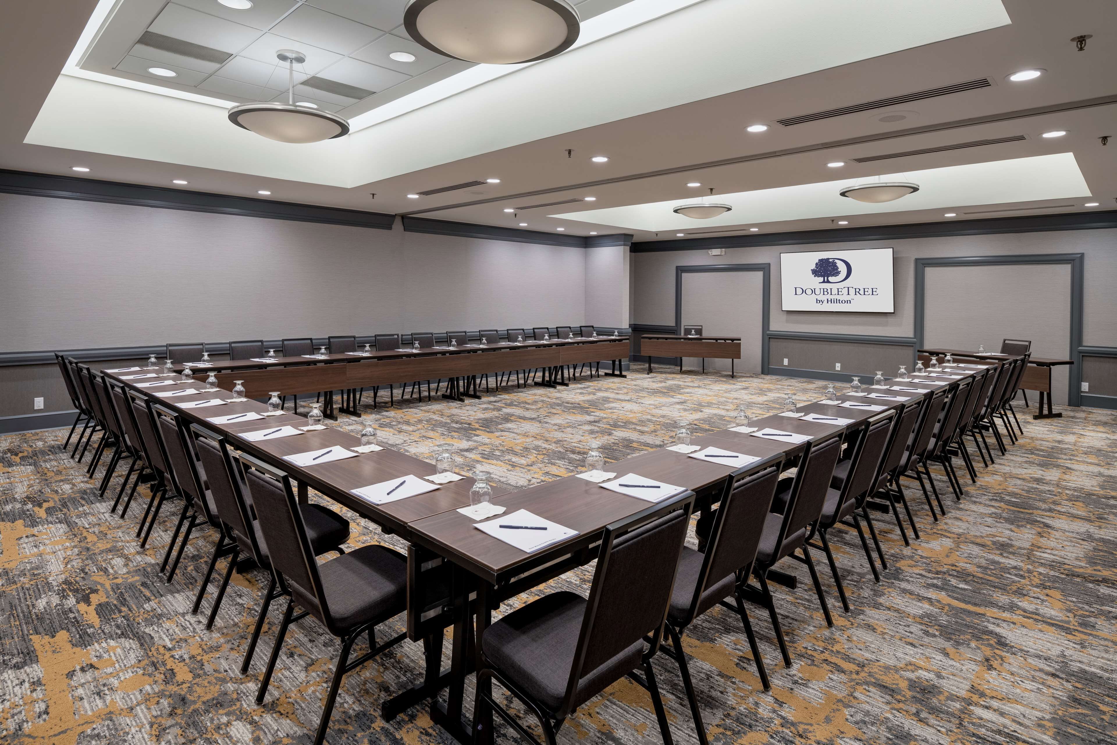 A conference room with a long table, chairs, and a logo on the wall.