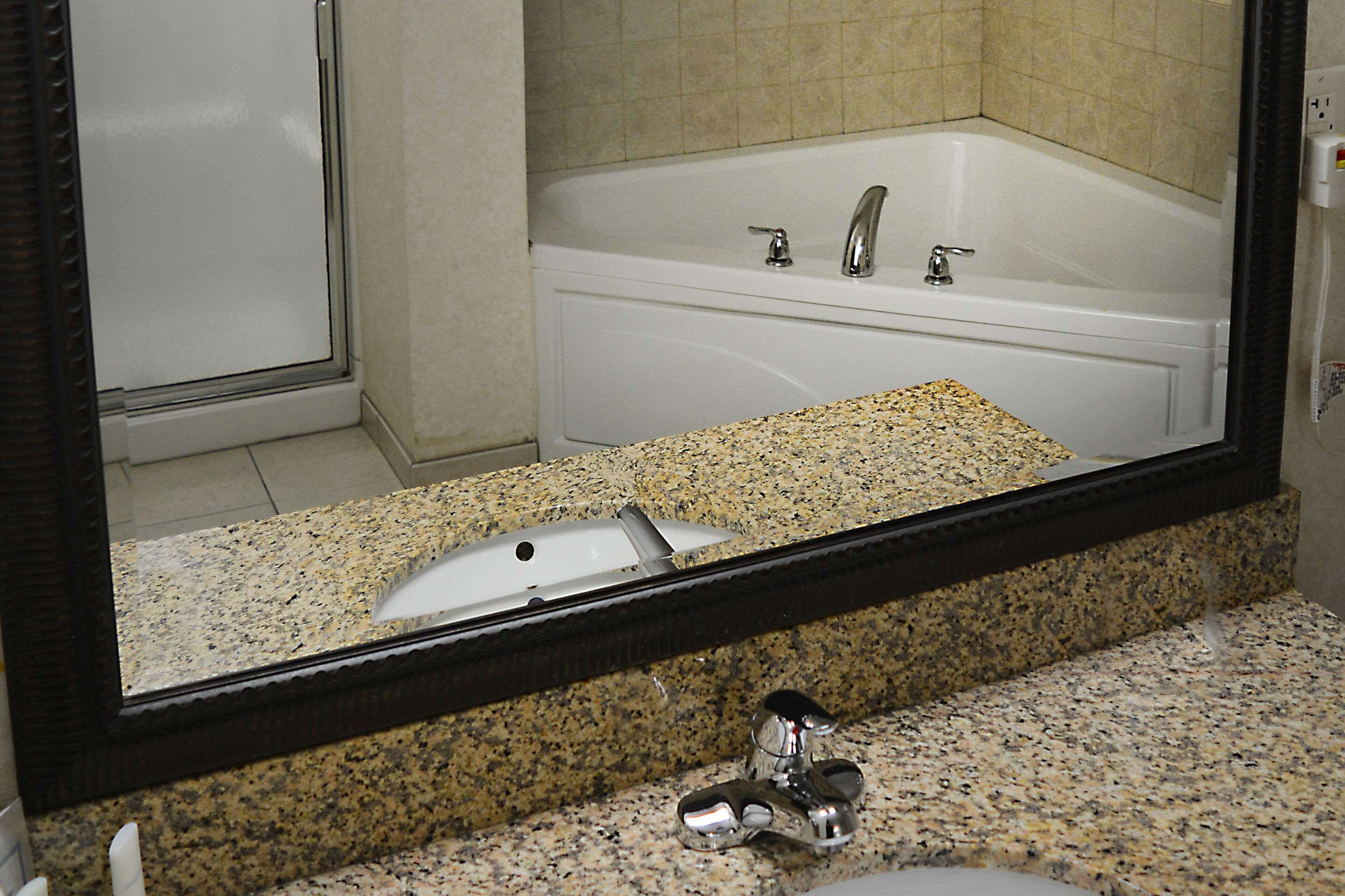 A bathroom with a granite countertop, a sink, and a bathtub.