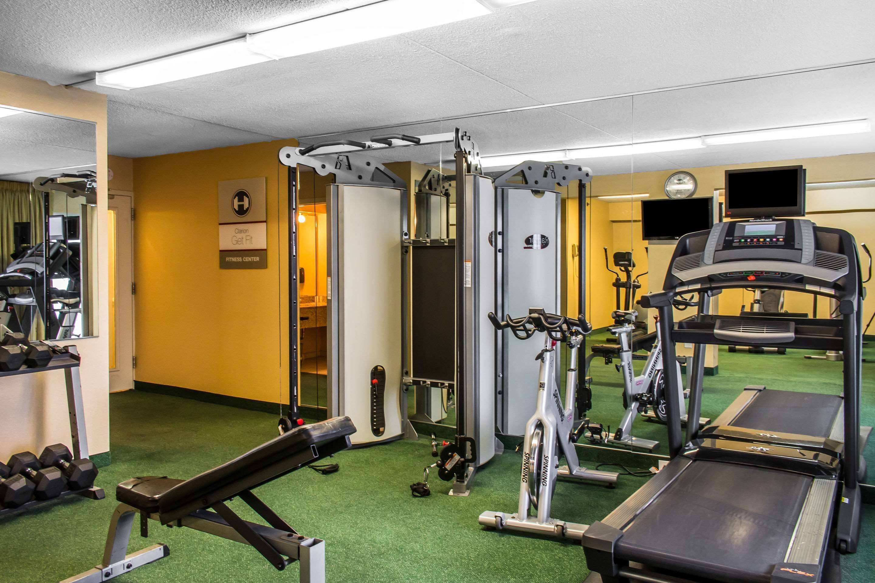 Et fitnesscenter med træningsudstyr, heriblandt et løbebånd, styrkemaskiner og et spejl.