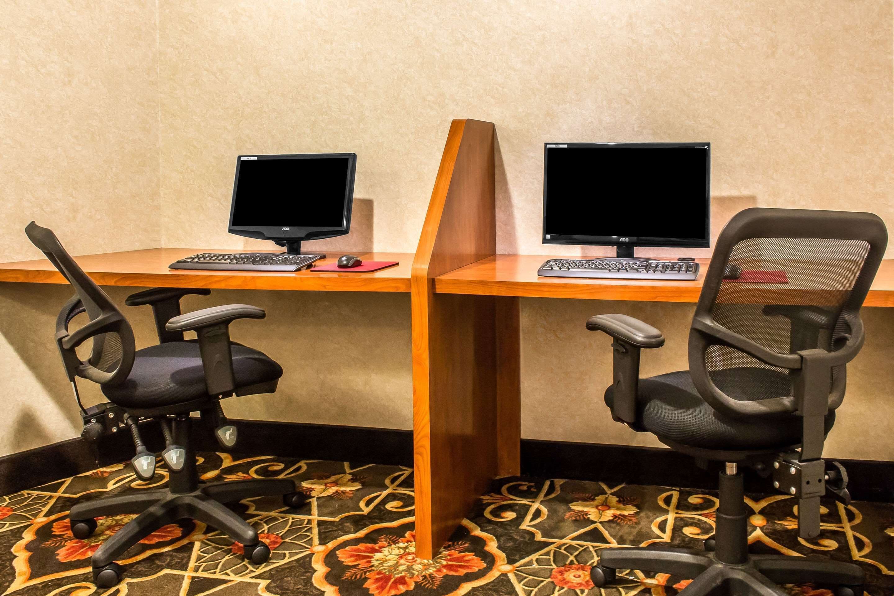 A workspace with two desks, each with a computer and keyboard, and two office chairs.
