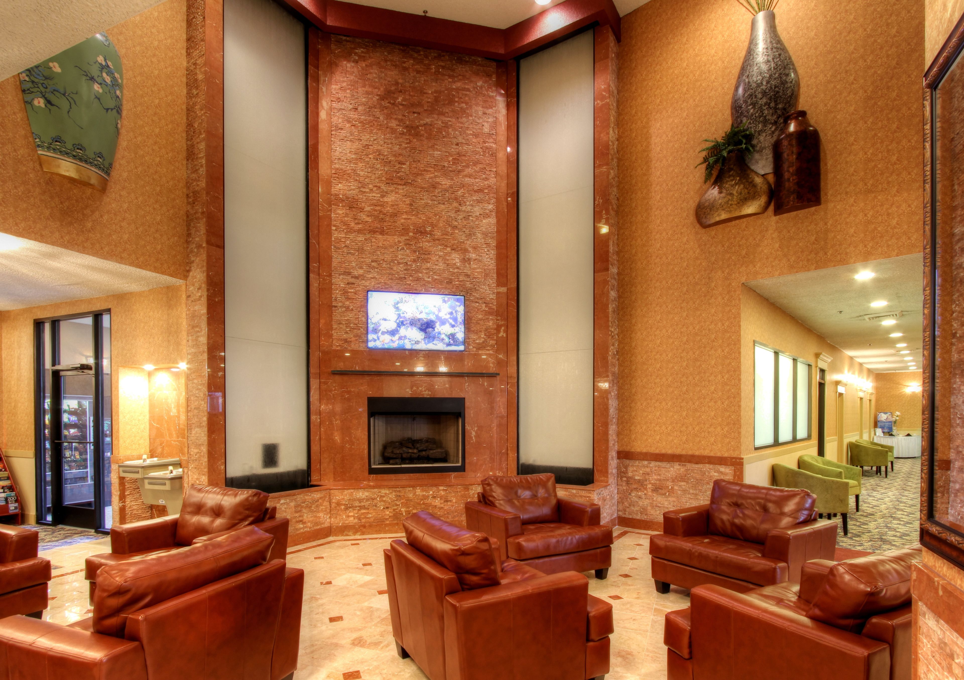 Eine Lobby mit Ledersofas, einem Kamin und einem Fernseher.