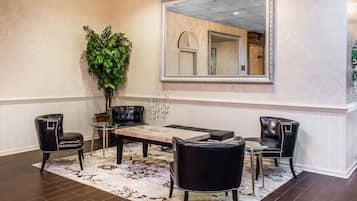 A dining area with a large mirror, two leather chairs, a glass table, and a patterned rug.