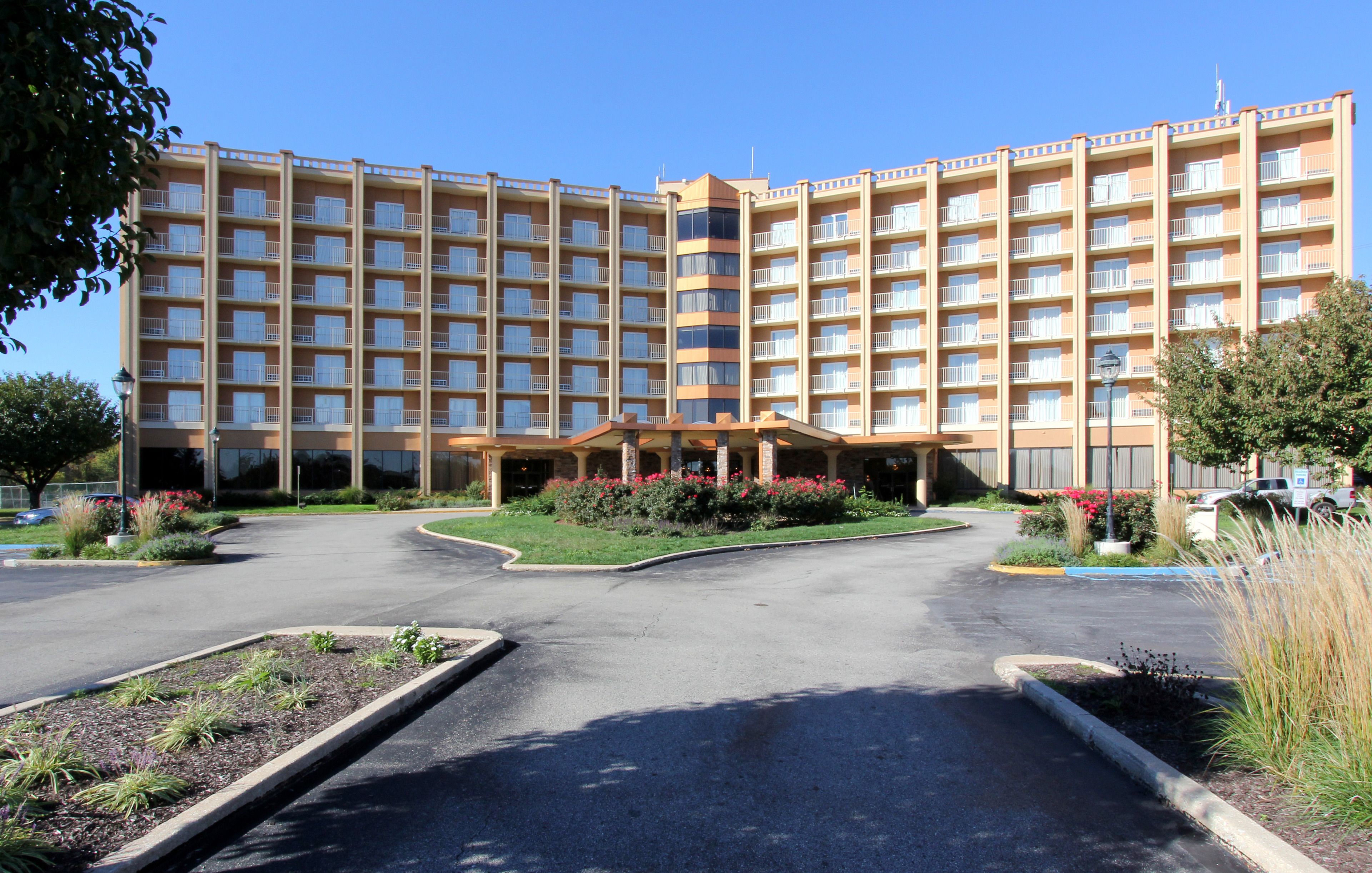 Ein großes, mehrstöckiges Hotel mit Innenhof, umgeben von einem Parkplatz und angelegten Gärten.