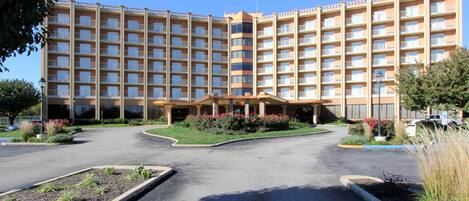 Ein großes, mehrstöckiges Hotel mit Innenhof, umgeben von einem Parkplatz und angelegten Gärten.