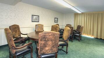 Une salle de conférence équipée d’une table ronde et de huit fauteuils rembourrés à ossature en bois.