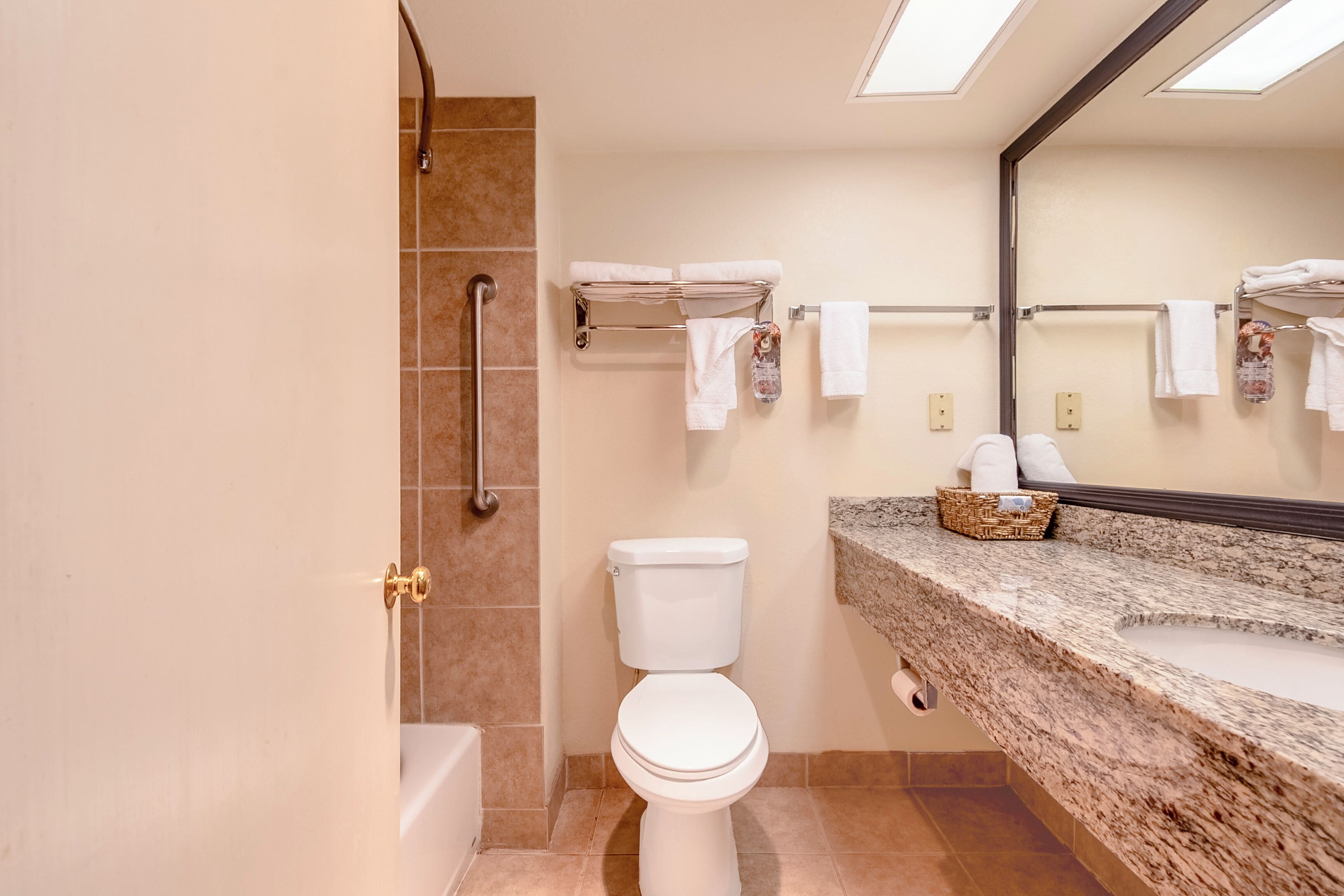 A bathroom with a toilet, a sink, a bathtub, and a handrail.