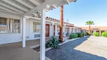 A motel with a white facade, a covered parking area, and a palm tree.