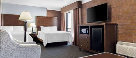Une chambre d’hôtel avec deux lits, une télévision, un bureau et une chaise.