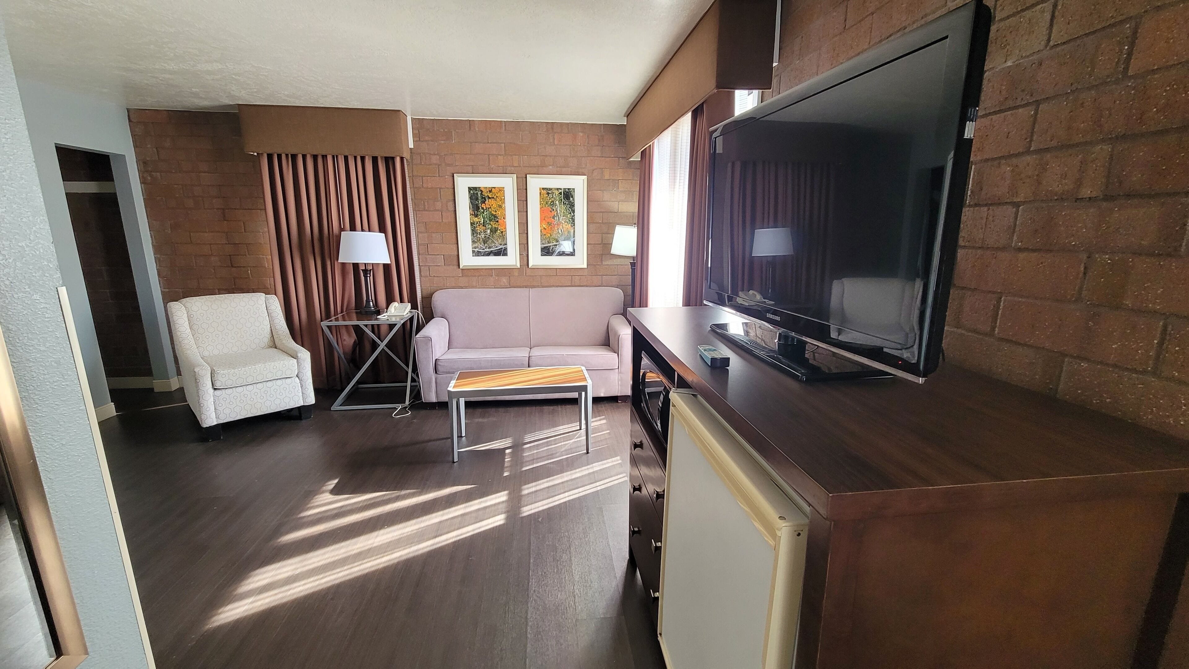 Een woonkamer met een bank, een salontafel, een televisie en een lamp.
