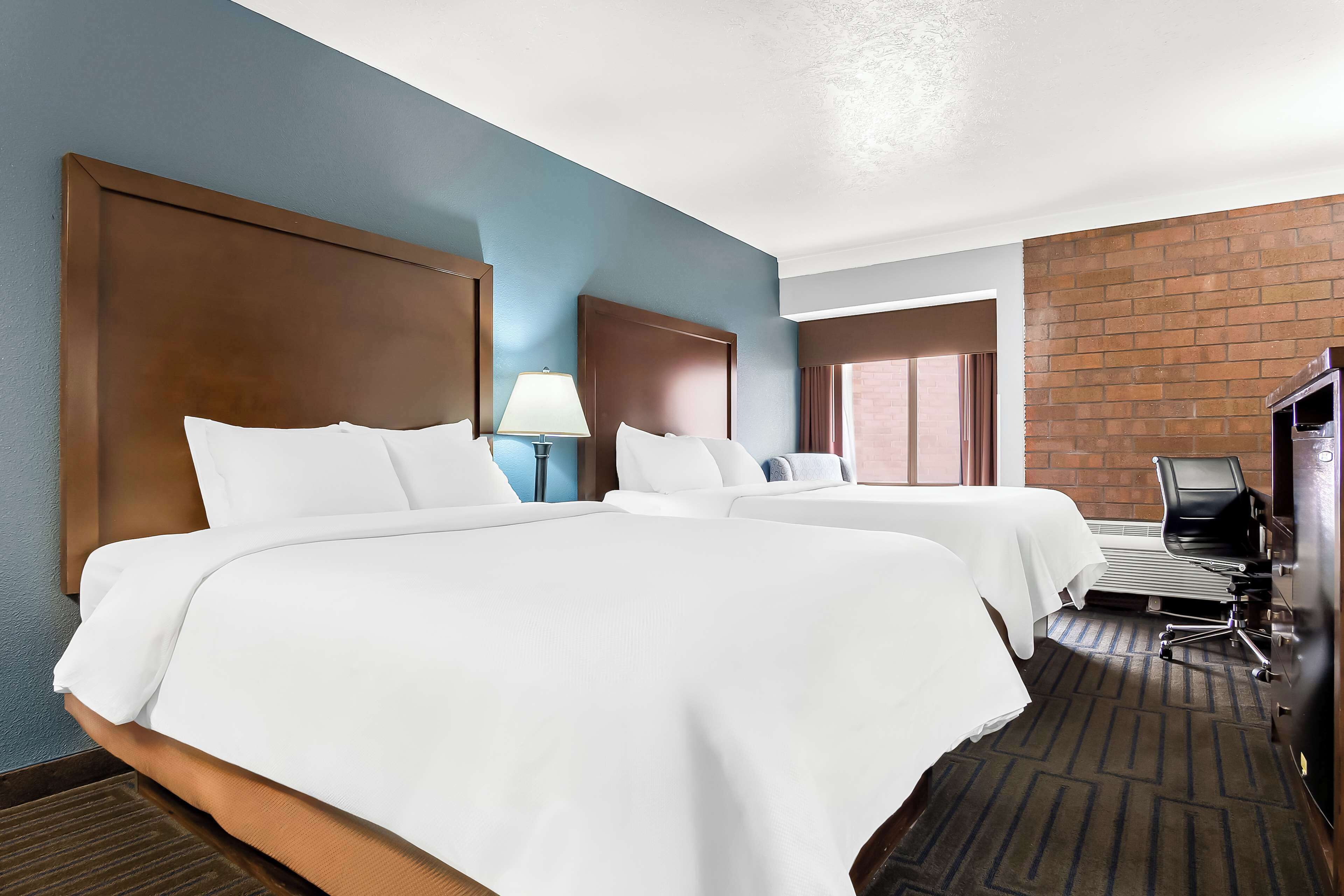Una habitación de hotel con dos camas, un escritorio, una silla y un televisor.