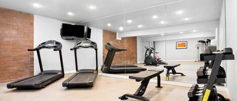 Een moderne sportschool met loopbanden, een hometrainer en gewichthefapparatuur.