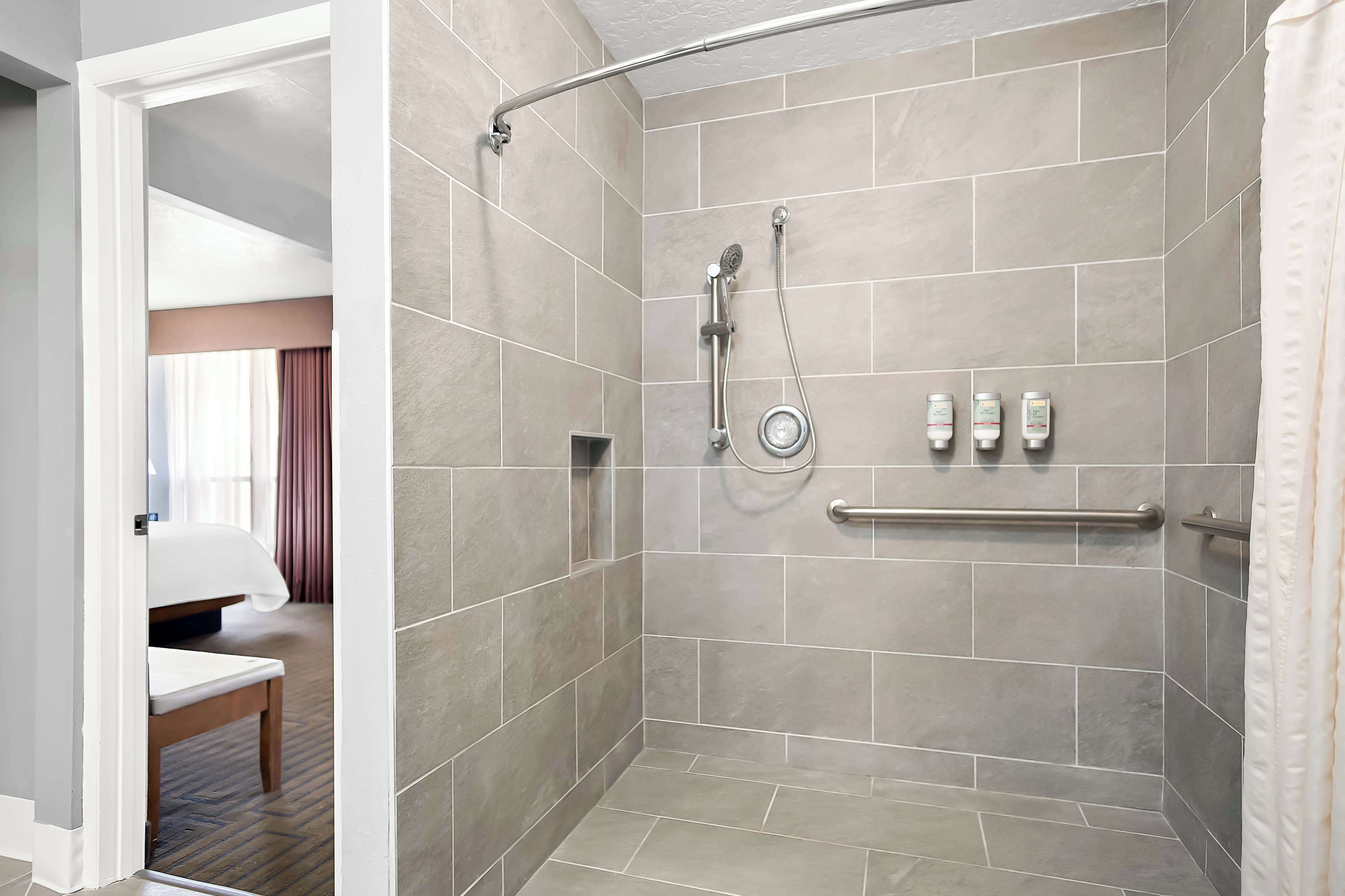 A shower with a glass door, a towel rack, and toiletries on the wall.