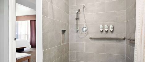 A shower with a glass door, a towel rack, and toiletries on the wall.
