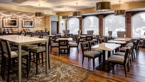 Un restaurant spacieux avec de hauts plafonds, de grandes fenêtres et différents types de sièges, notamment des tables et des banquettes.