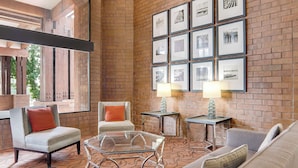 Un espace de détente moderne avec un mur en briques, des tableaux encadrés et des sièges confortables.