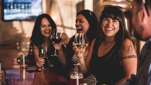 Un grupo de personas sentadas en un bar con copas de vino.