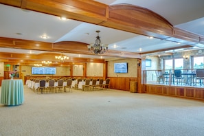 A conference room with a long table, chairs, a chandelier, and a large window with a view.