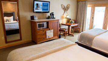 A hotel room with a bed, a desk with a computer, a television, and a view of the outdoors.