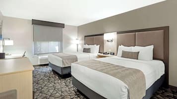 Una habitación de hotel con dos camas, un escritorio y una alfombra estampada.