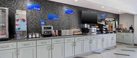 Eine moderne Hotelhalle mit einem Selbstbedienungsbereich für das Frühstück, inklusive Kaffeemaschine, Toaster und Kühlvitrine.