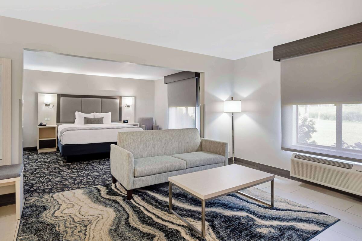 A modern hotel room with a bed, sofa, and a small table.