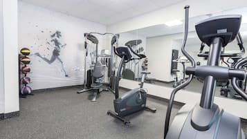 Une salle de sport équipée de machines de cardio, de machines de musculation et dotée d’un mur recouvert de miroirs.