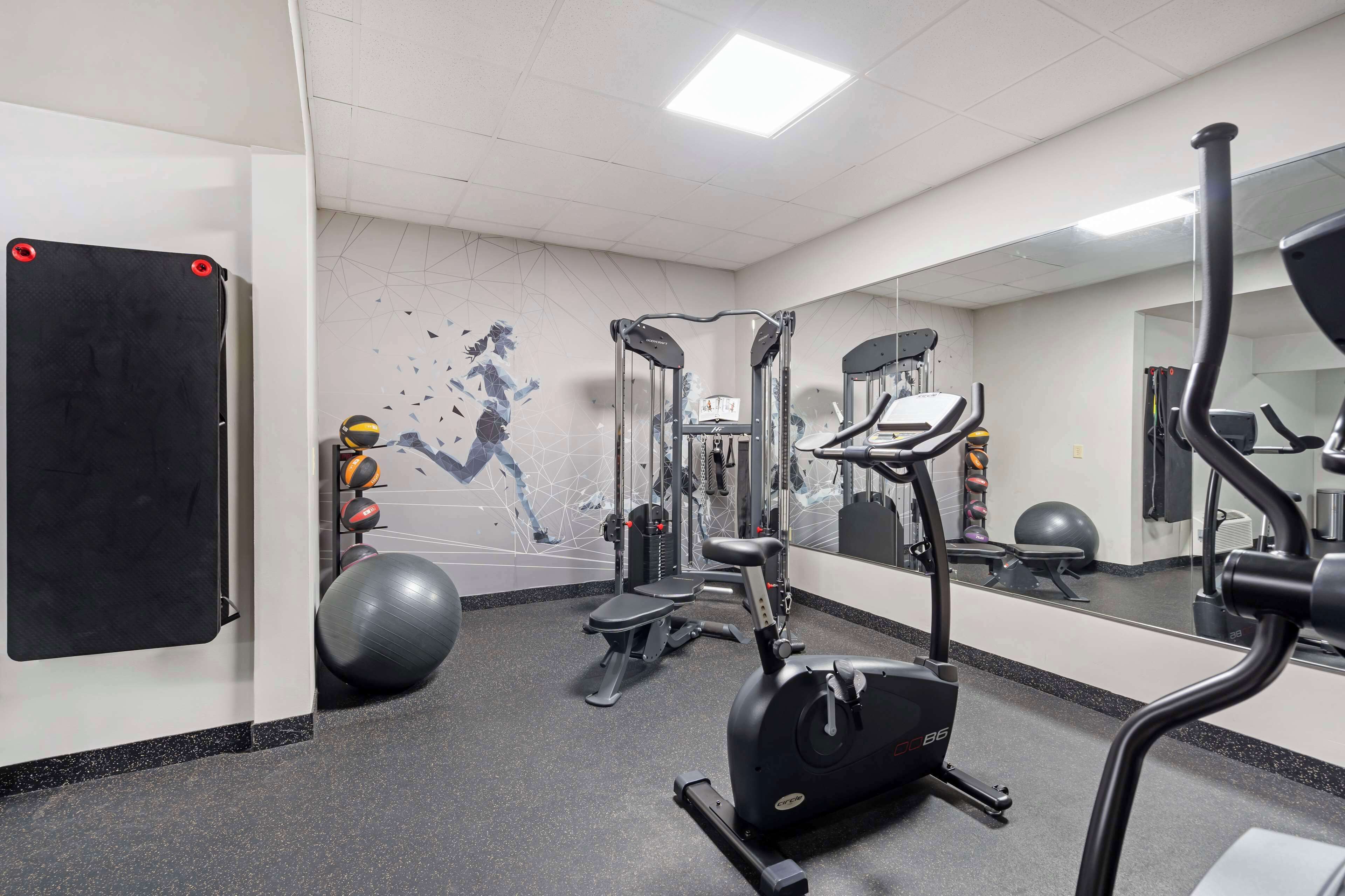 A gym with exercise equipment, a mirrored wall, and a geometric wall design.