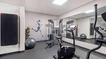 A gym with exercise equipment, a mirrored wall, and a geometric wall design.